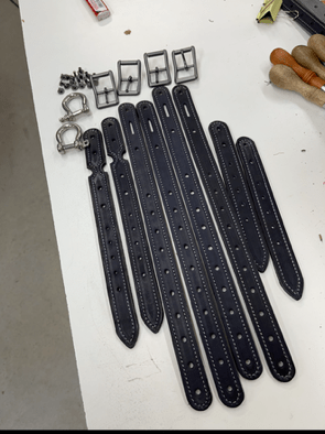 Black leather straps on a white surface with small metal components.