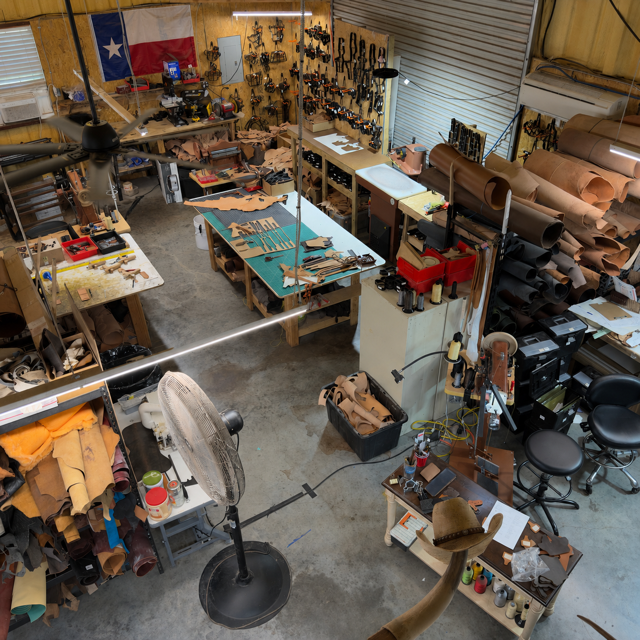 Inside the Busted B Leather workshop in Lone Oak, Texas — hand tools, leather, and a finished holster on the bench